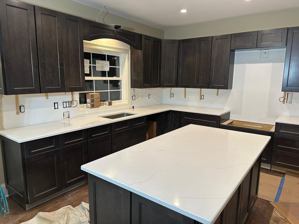 A kitchen with dark cabinets and white counter tops is being remodeled.