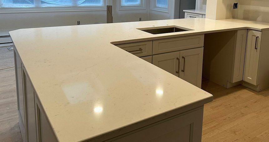 A kitchen with white cabinets and a large island with a sink.