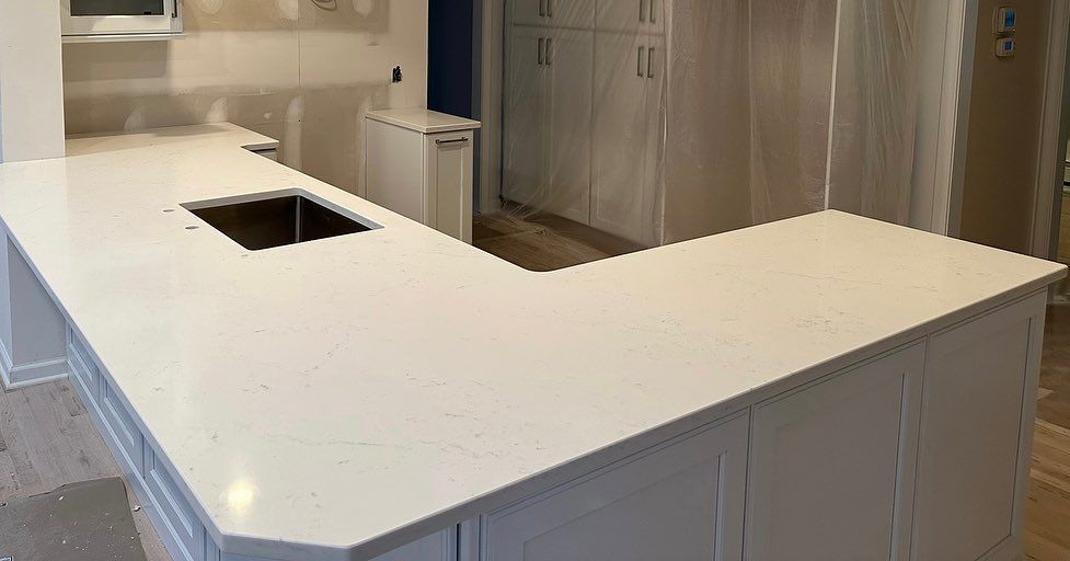 A kitchen with white cabinets and a white counter top with a sink.