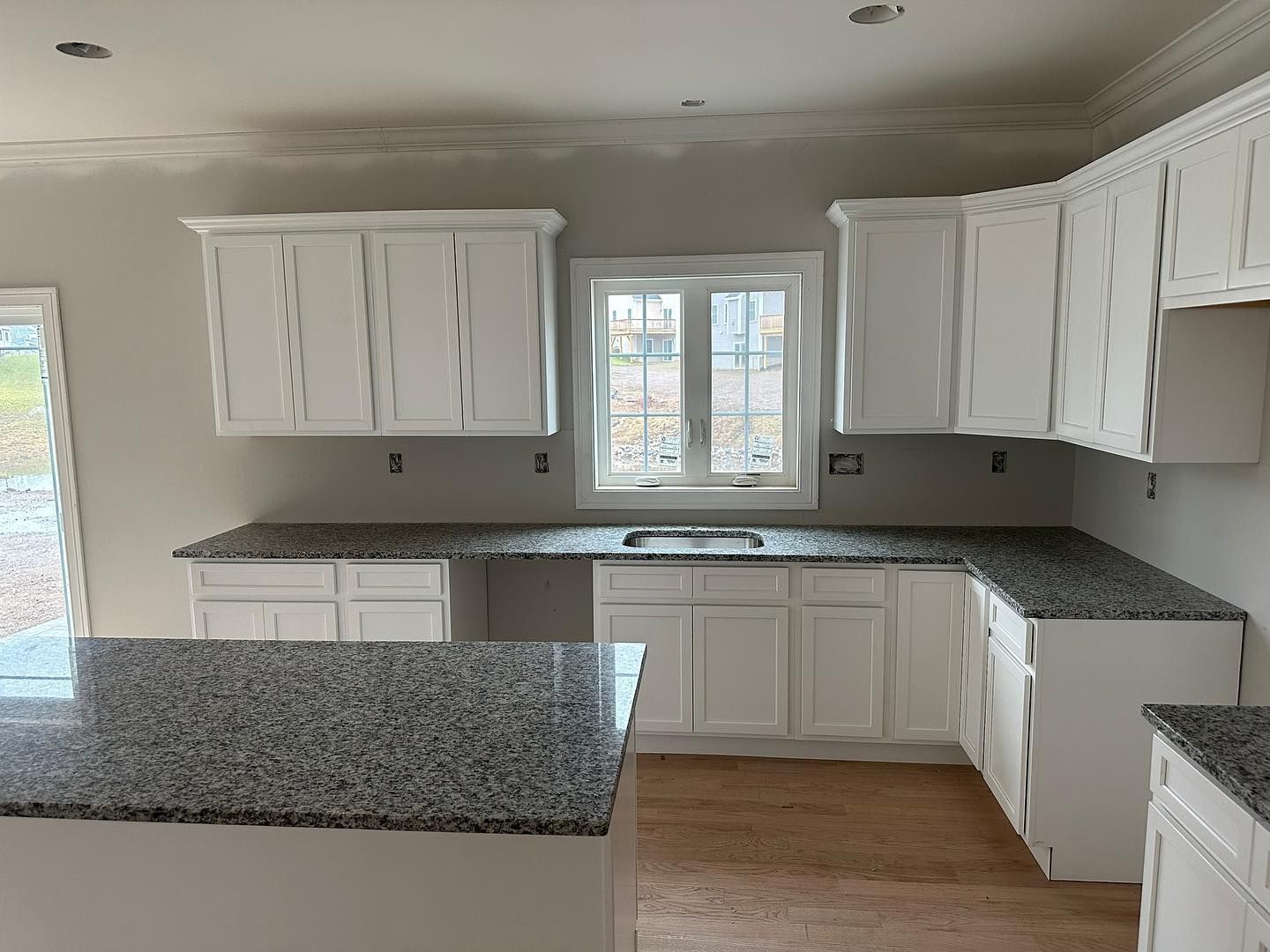 A kitchen with white cabinets and granite counter tops.