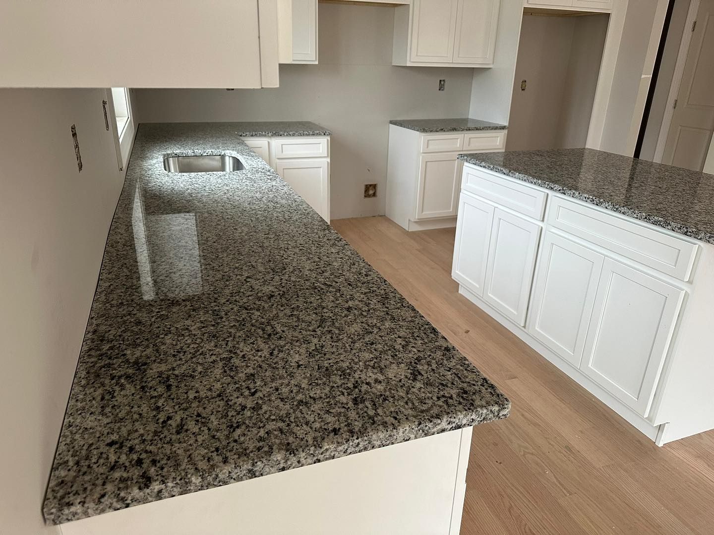 A kitchen with granite counter tops and white cabinets