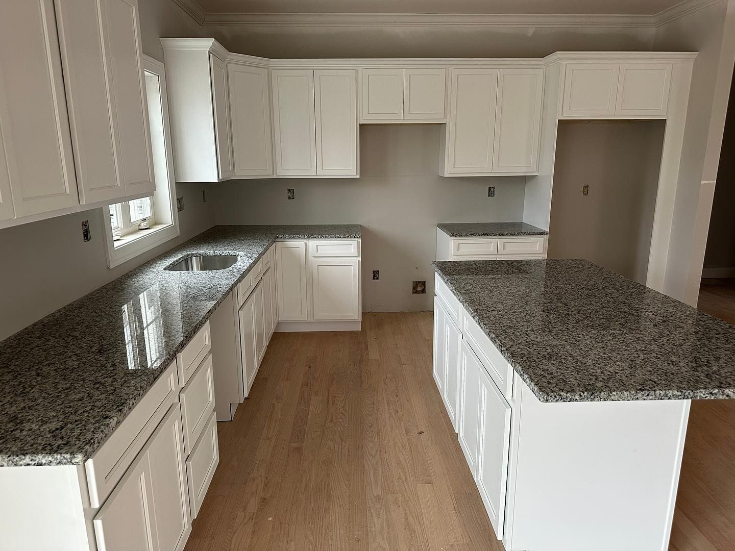 A kitchen with white cabinets and granite counter tops.