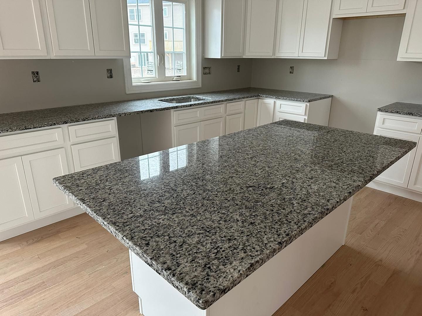 A kitchen with granite counter tops and white cabinets.