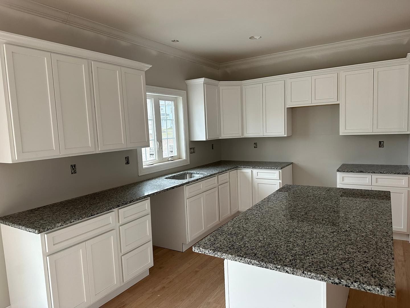 A kitchen with white cabinets and granite counter tops
