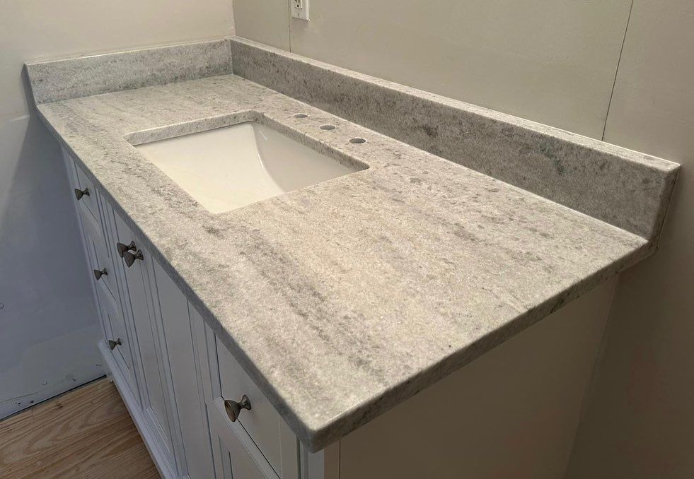 A bathroom vanity with a granite counter top and a sink.