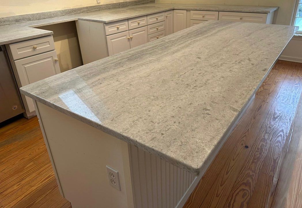 A kitchen with white cabinets and a large granite counter top.