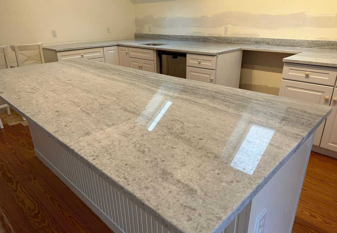 A kitchen with a large granite counter top and white cabinets.