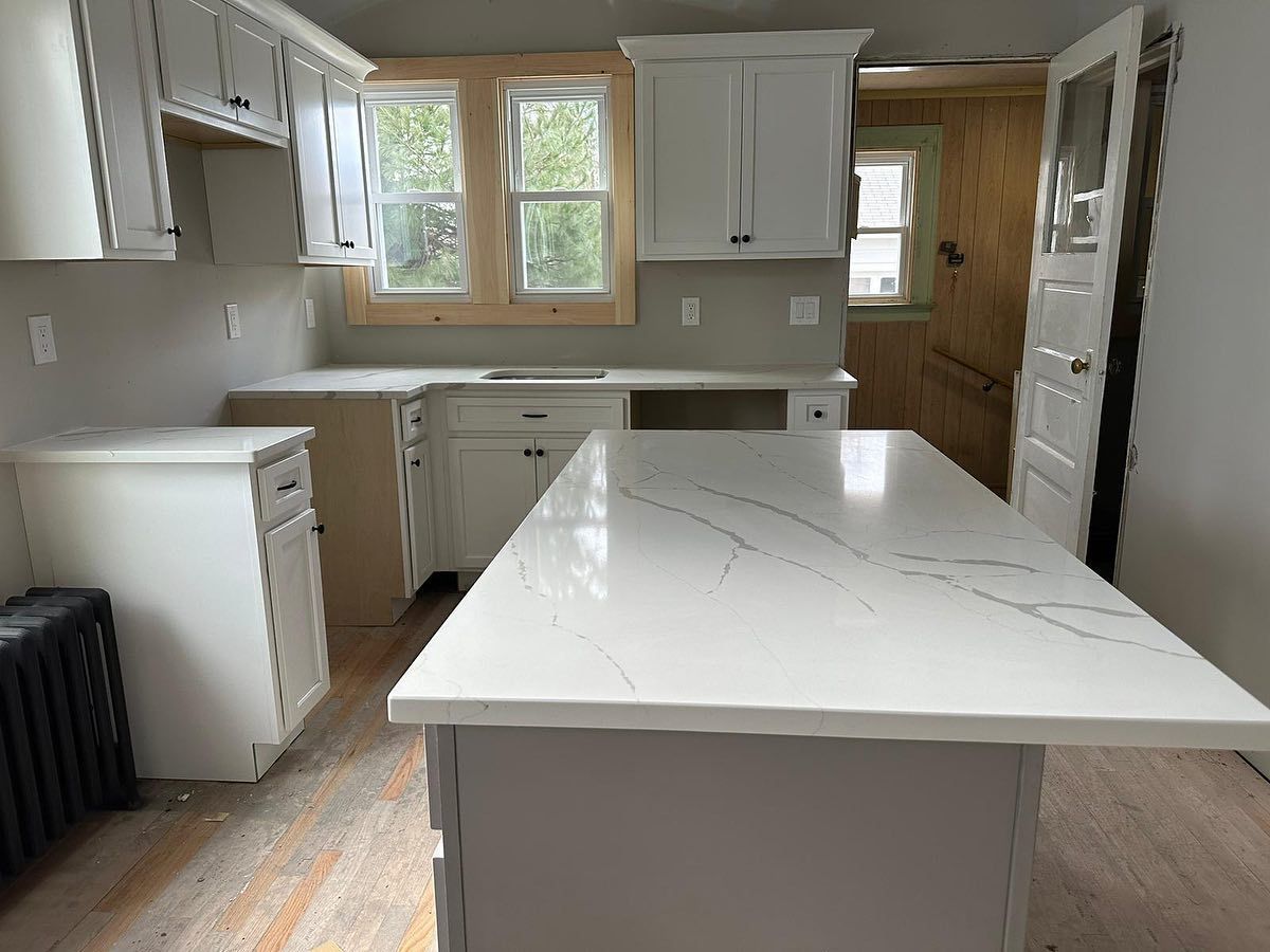 A kitchen with white cabinets and a large island in the middle.