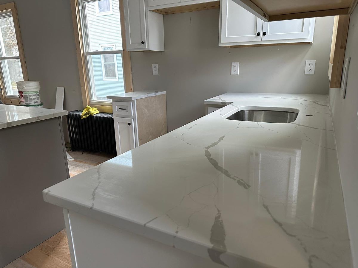 A kitchen with white cabinets , granite counter tops , and a sink.