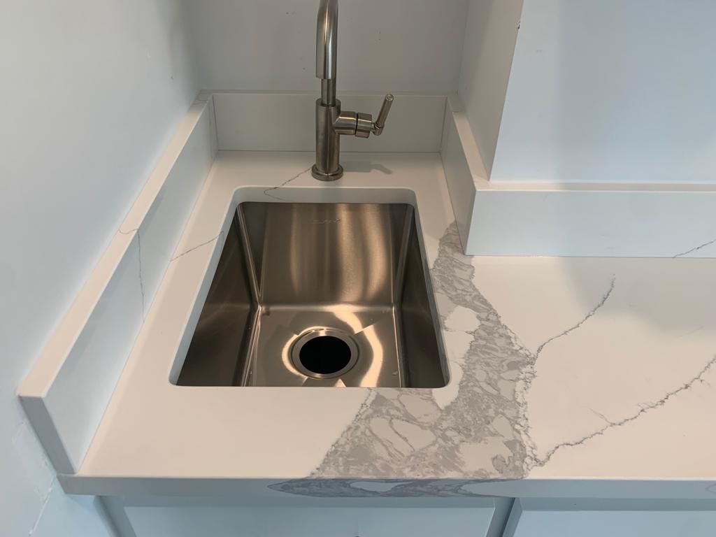 A stainless steel sink is sitting on top of a white counter.