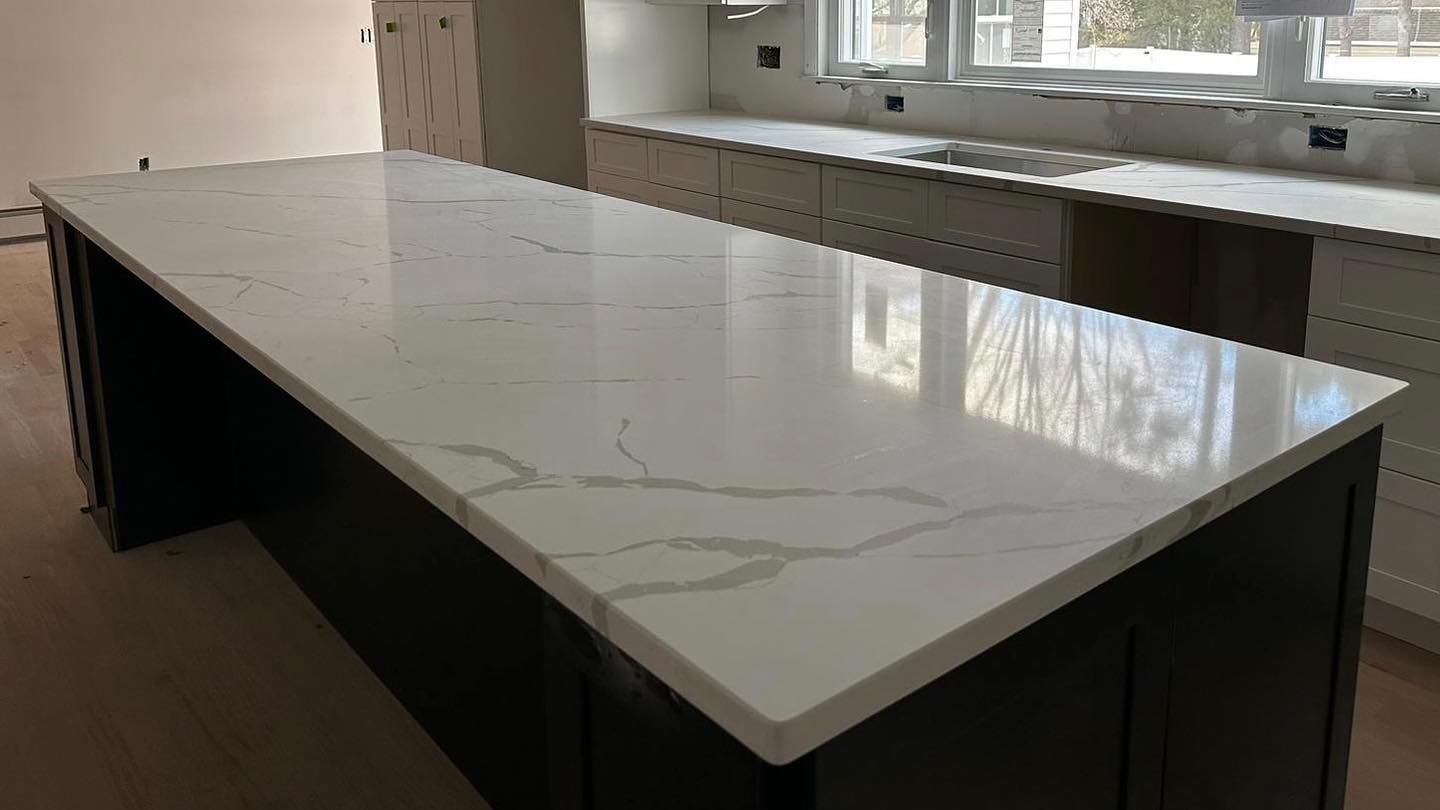 A kitchen with a long white counter top and black cabinets.