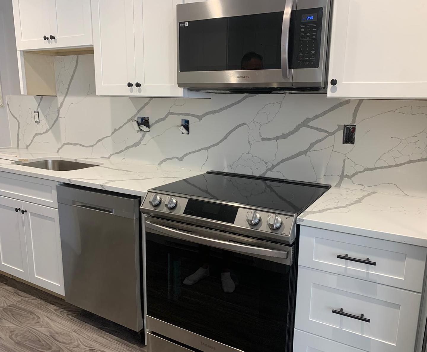 A kitchen with a stove , microwave , sink and dishwasher.