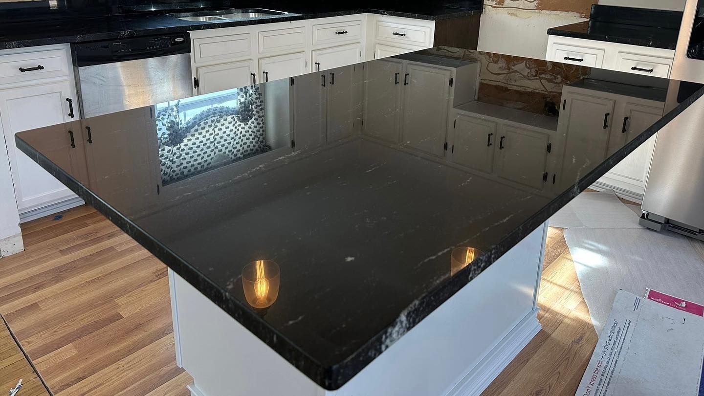 A kitchen with a black granite counter top and white cabinets.
