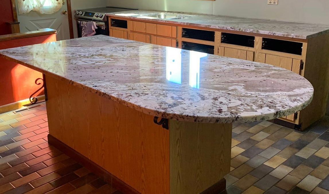 A kitchen with a large granite counter top and wooden cabinets.