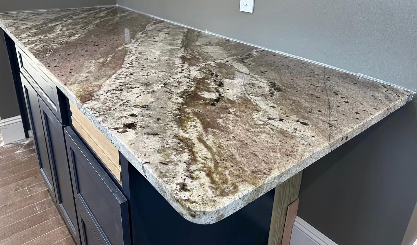A kitchen counter with a granite counter top and blue cabinets.