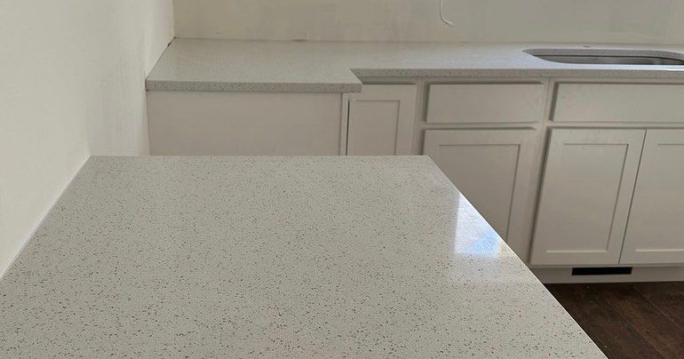 A kitchen with white cabinets and a white counter top.