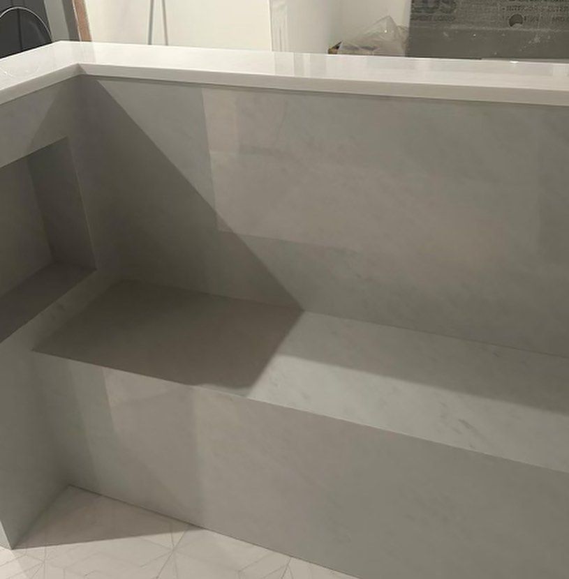 A white bench with a white counter top is sitting in a room.