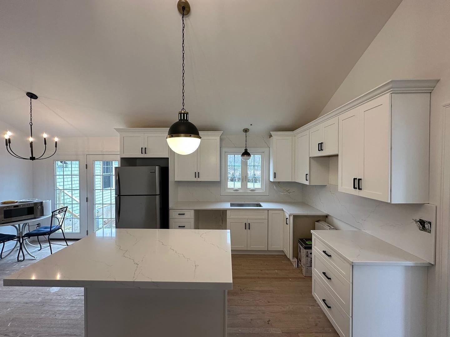 A kitchen with white cabinets and a large island in the middle