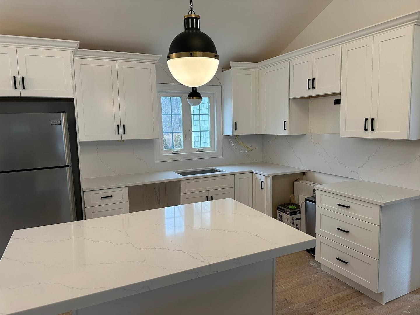 A kitchen with white cabinets , stainless steel appliances , and a large island.