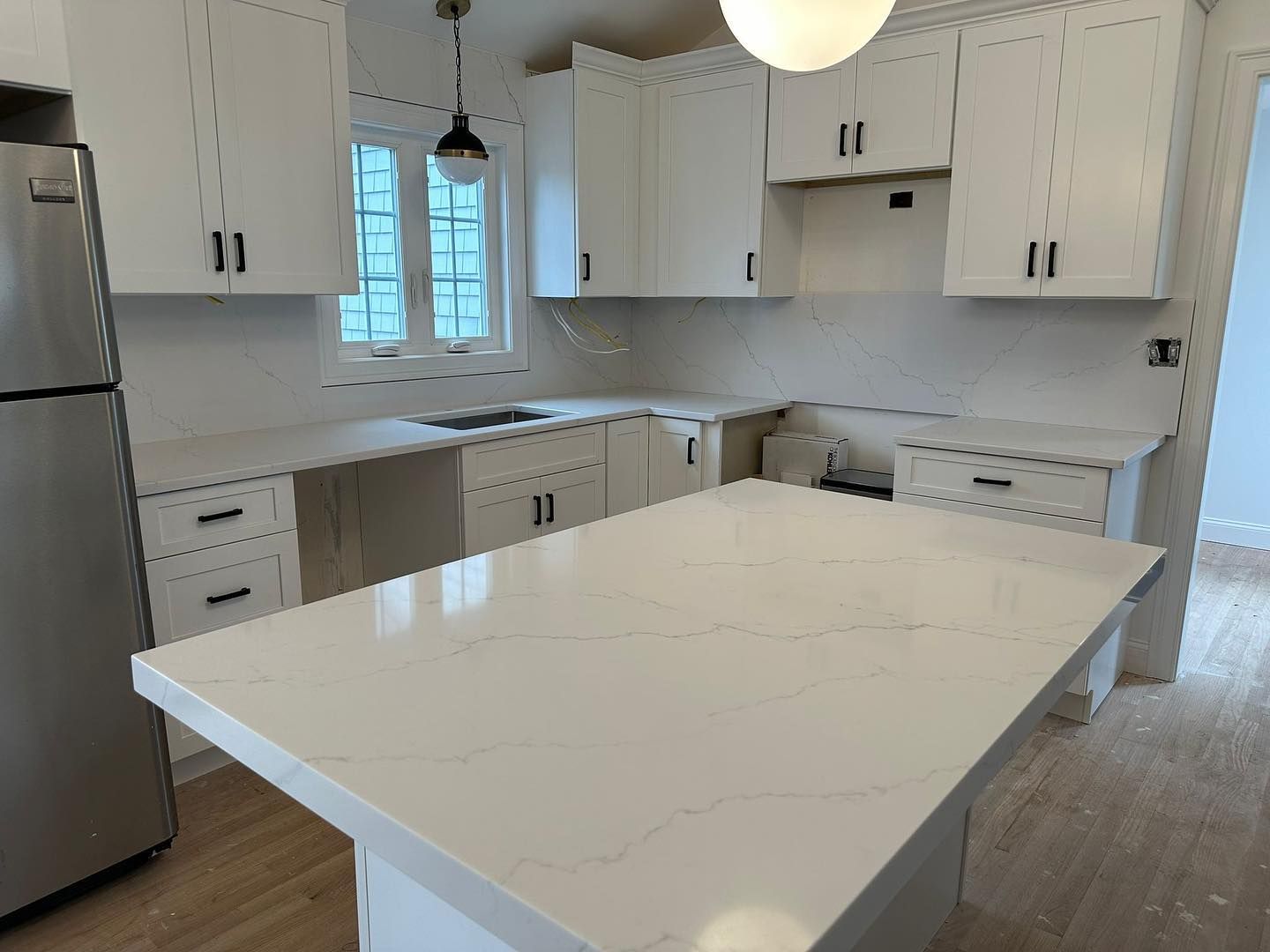 A kitchen with white cabinets and a large island in the middle.