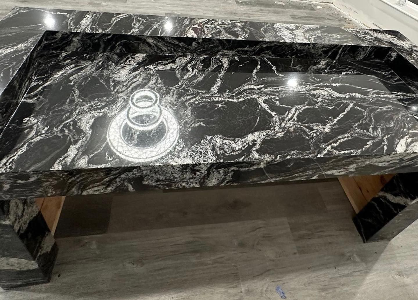 A black and white marble coffee table is sitting on a wooden floor.