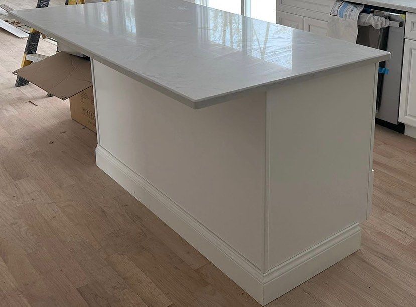 A large white island in a kitchen with a white counter top.