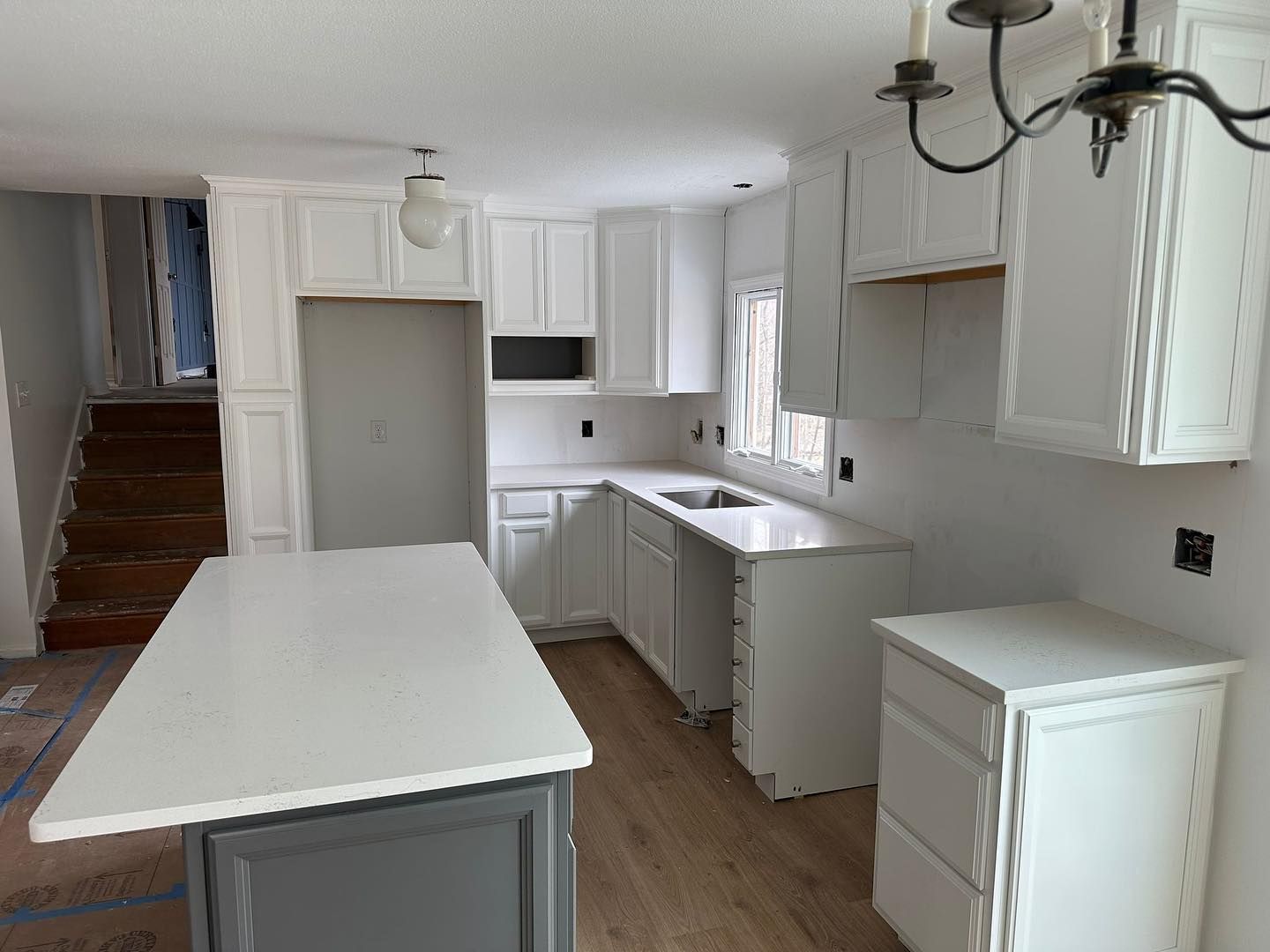 A kitchen with white cabinets and a large island in the middle.