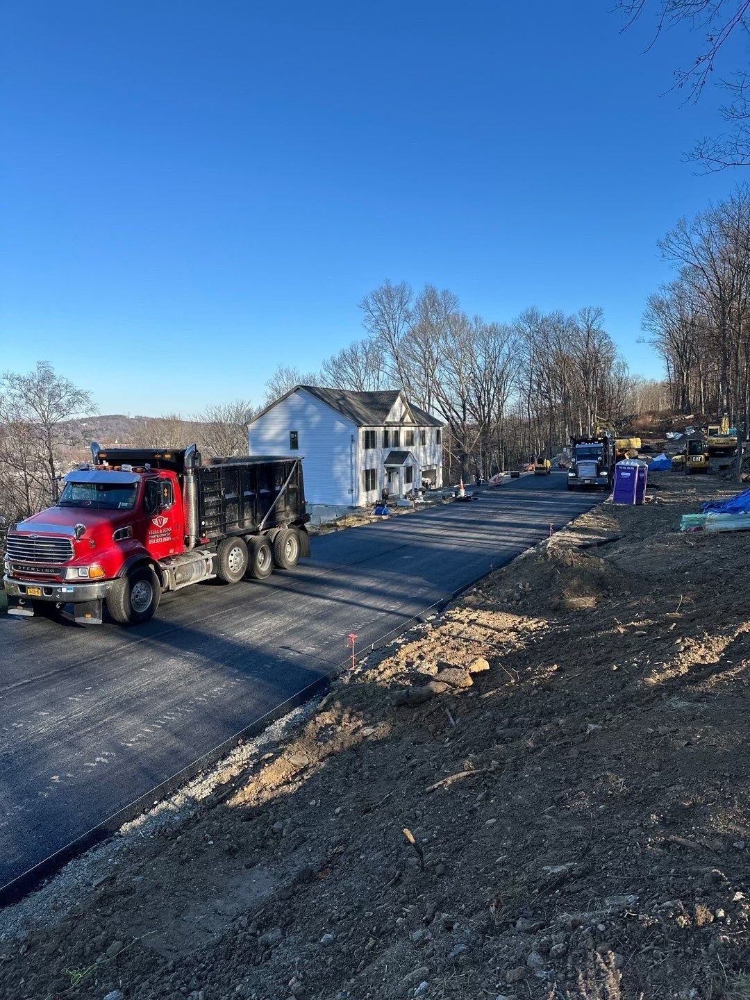 A red dump truck is parked on the side of a road.