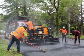 A group of construction workers are working on a road.