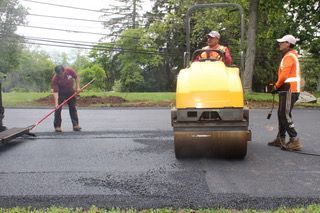 A yellow roller is being used to spread asphalt on a road.