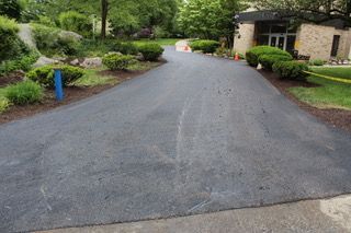 A asphalt driveway leading to a house in a residential area.