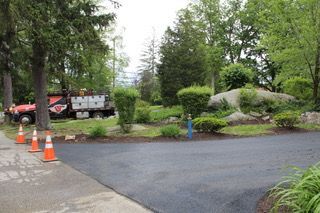 A red truck is parked in a driveway next to a row of orange cones.