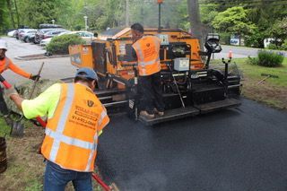 A man in an orange vest is standing next to a machine.