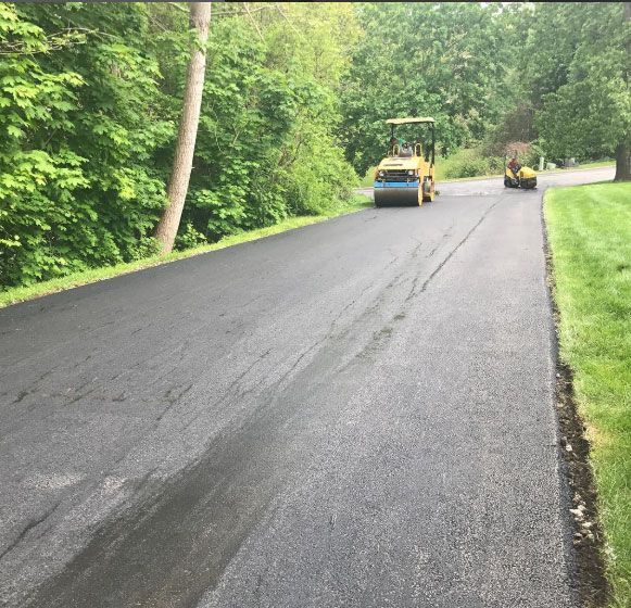 A tractor is driving down a road with trees in the background