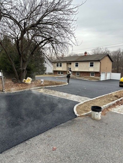 A man is standing in a driveway next to a house.
