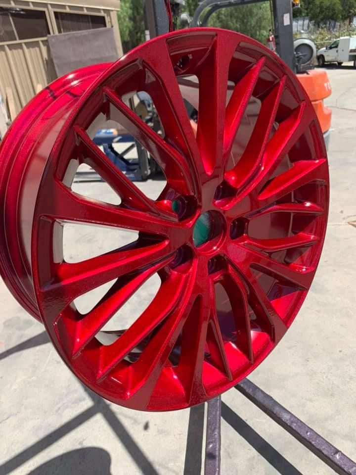 A red car wheel is sitting on a metal stand.