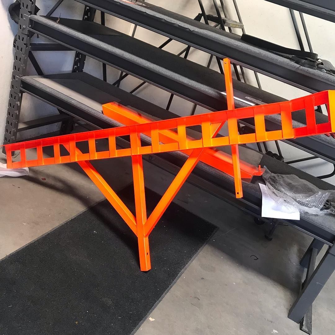 An orange ladder is sitting on top of a black shelf