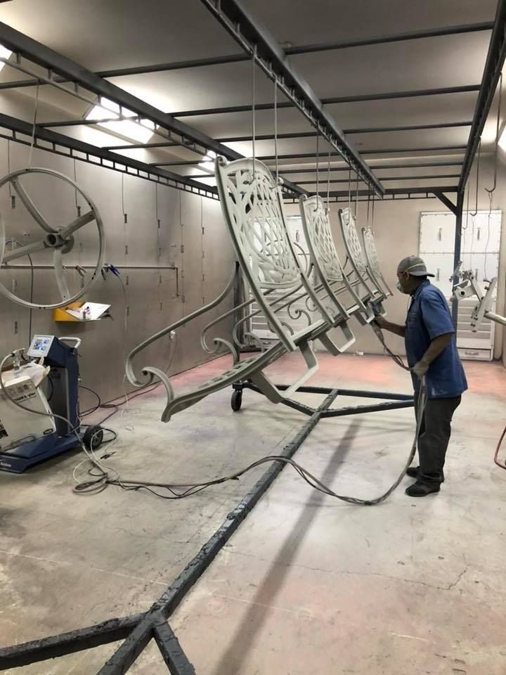 A man is painting a row of chairs in a room.