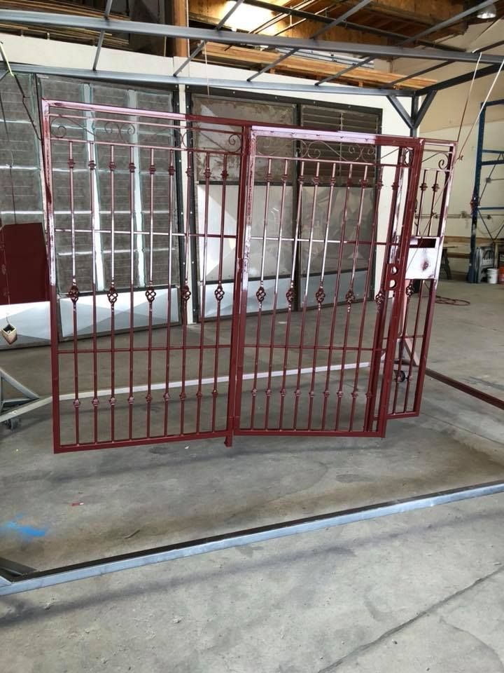 A red wrought iron gate is sitting in a warehouse.