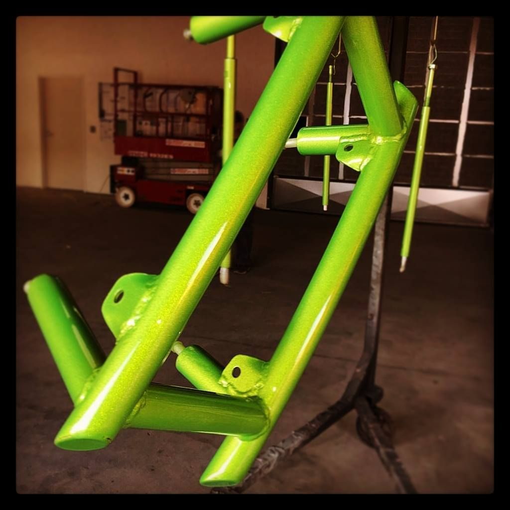 A green bicycle frame is sitting on a stand