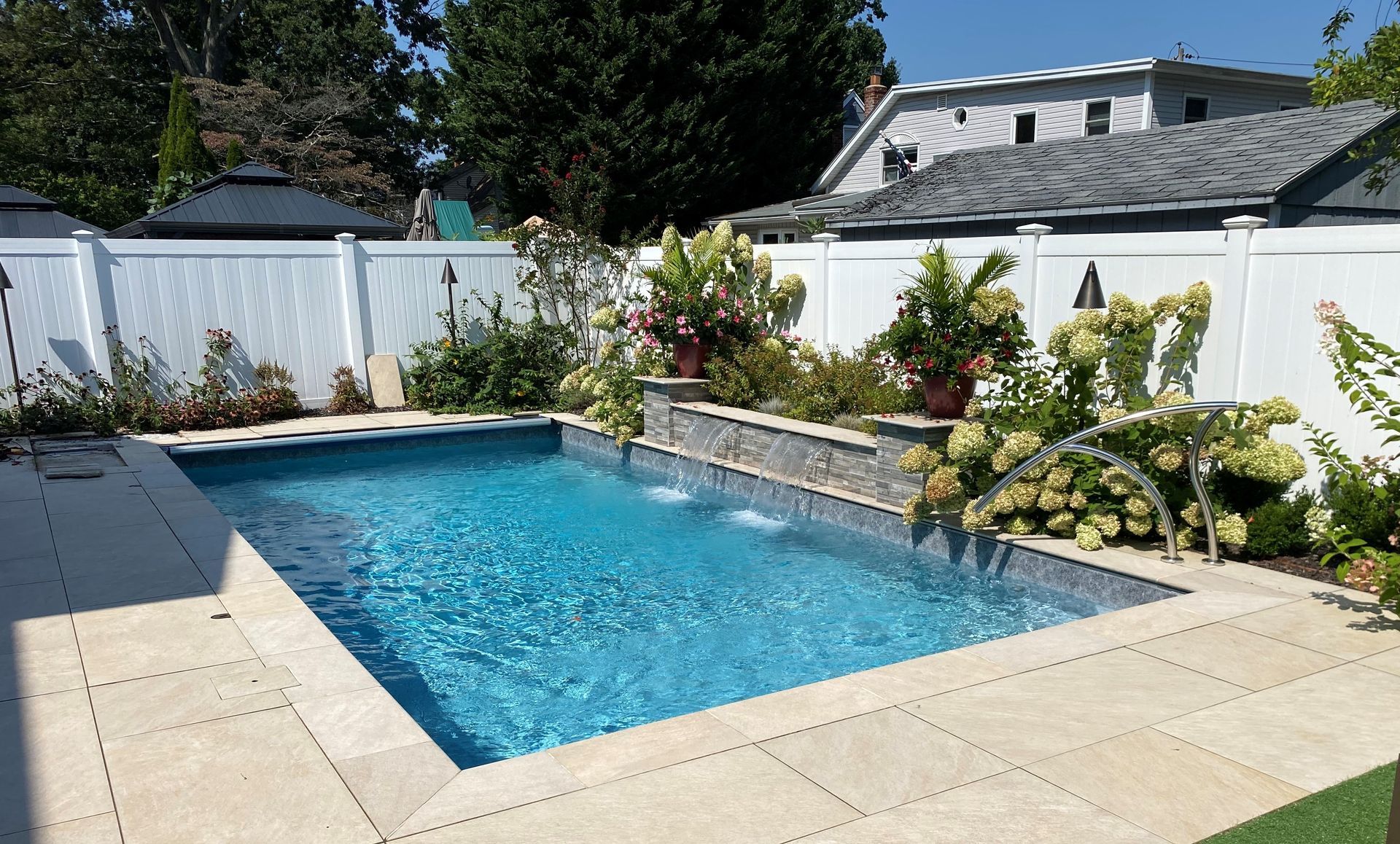 A large swimming pool with a waterfall in the backyard