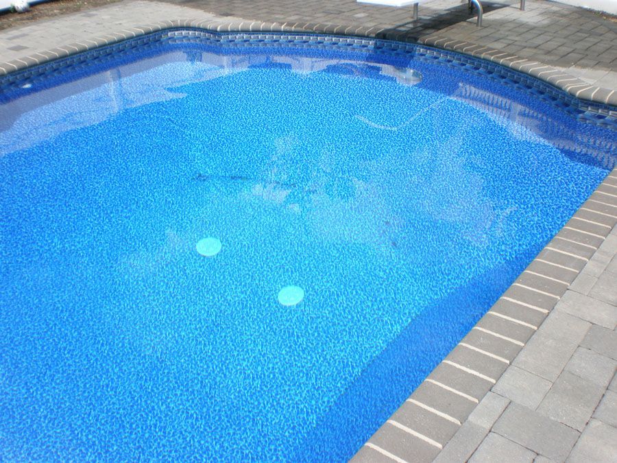 A swimming pool with blue water and a brick border