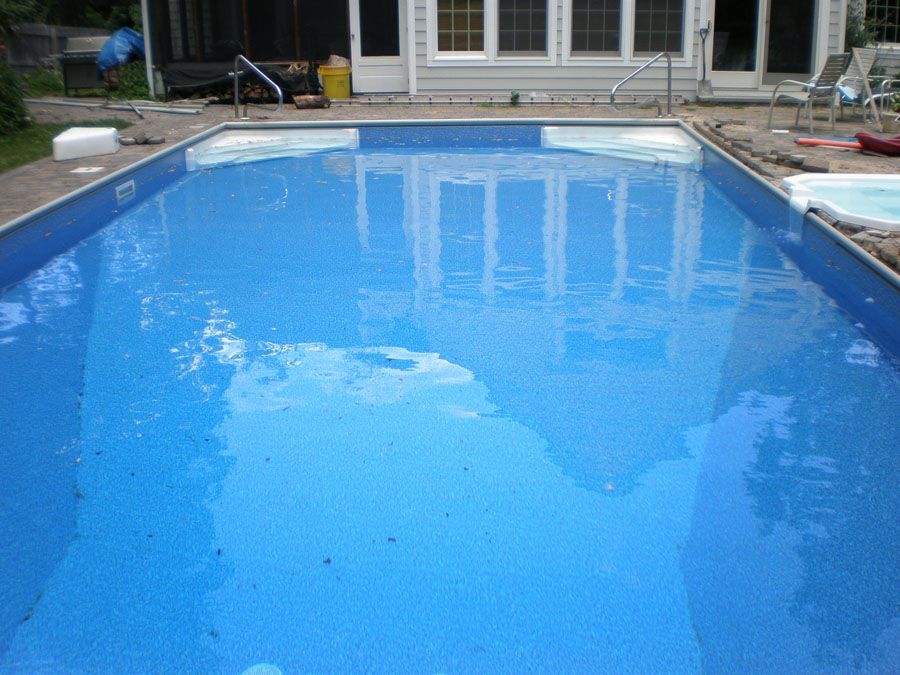 A large swimming pool is being built in the backyard of a house.