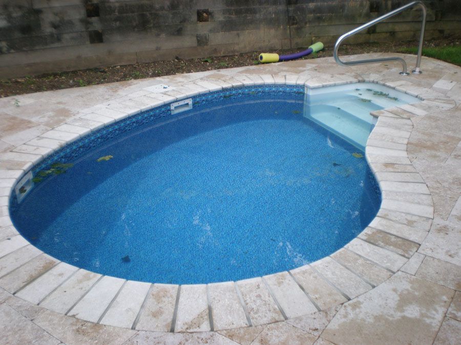 A small oval shaped pool with stairs leading to it
