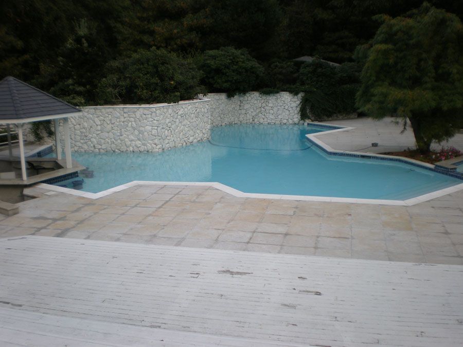 A large swimming pool with a gazebo in the background
