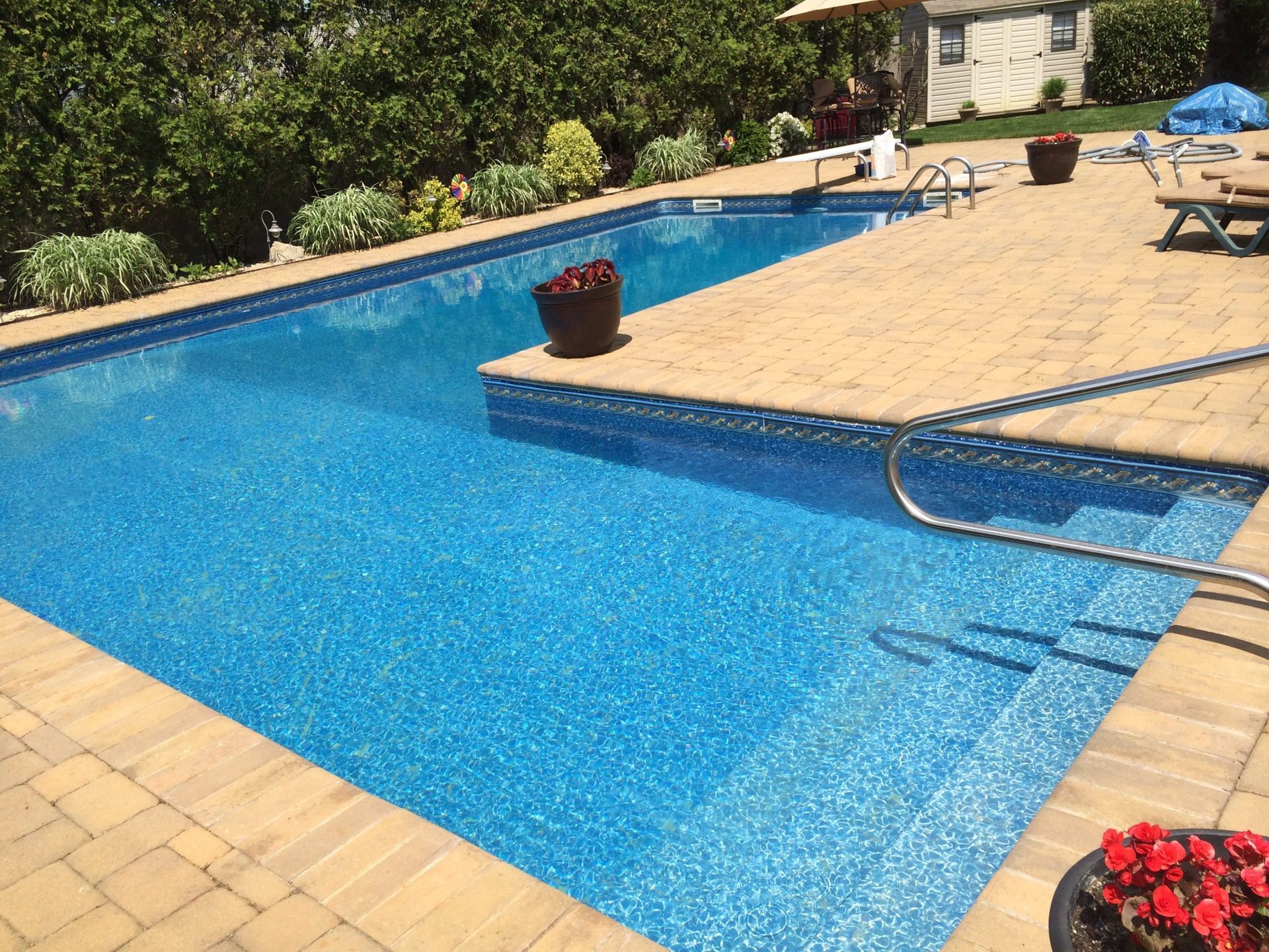 A large swimming pool is surrounded by a brick patio.