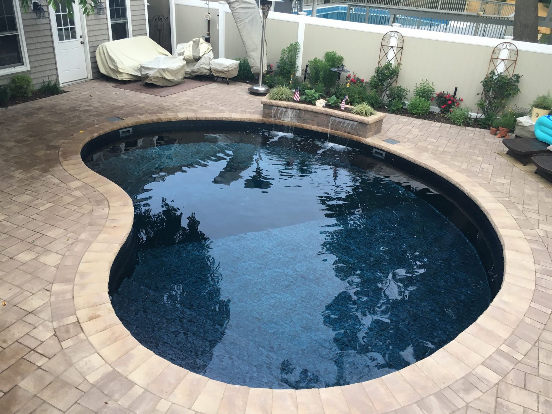 A large kidney shaped swimming pool in a backyard