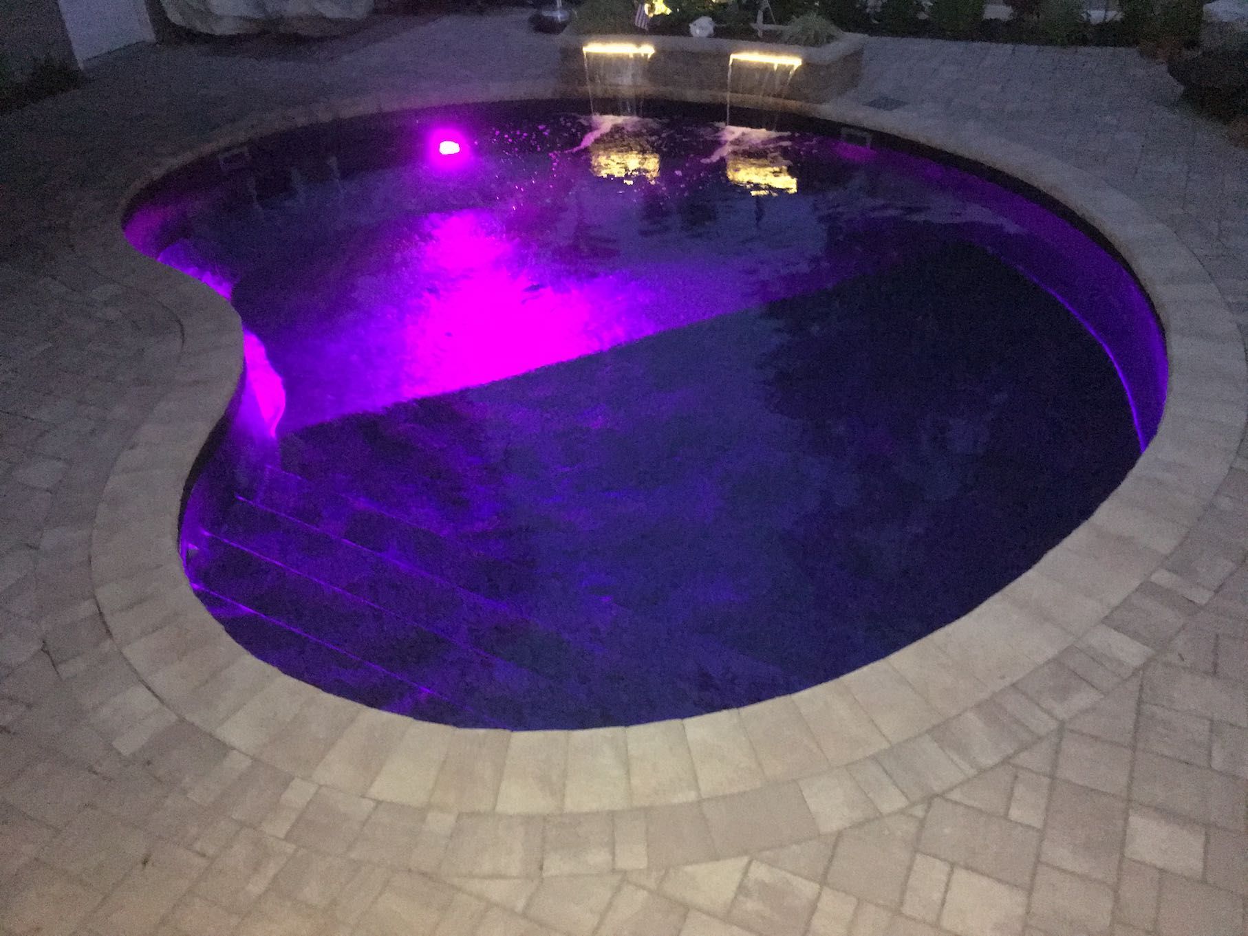 A swimming pool with purple lights on it at night