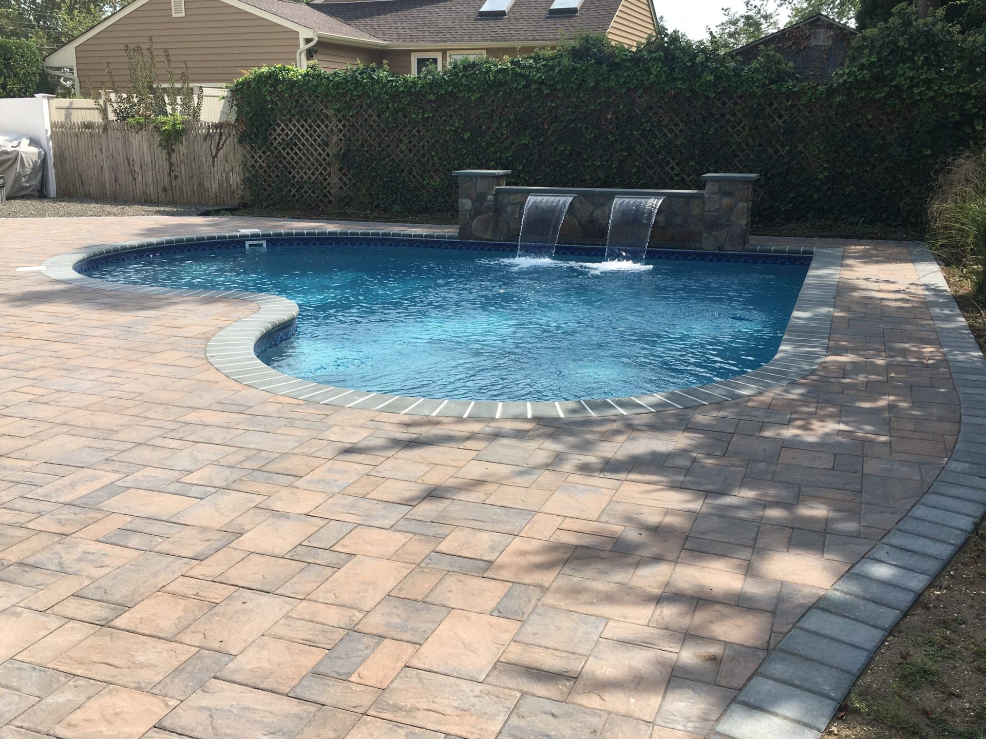 A large swimming pool with a waterfall in the backyard