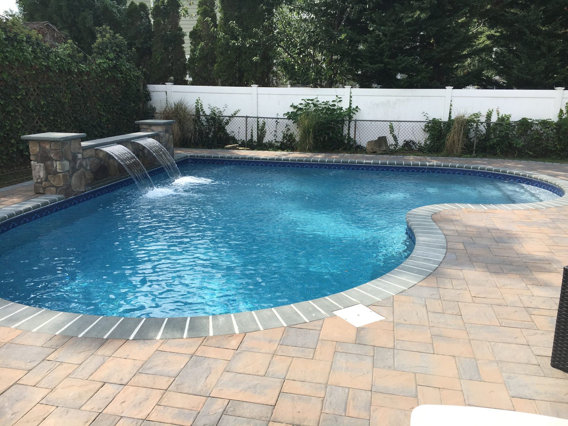 A large swimming pool with a waterfall on the side